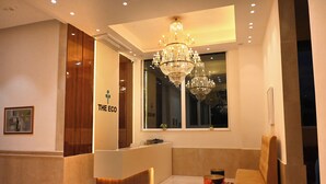 A hotel reception area with a modern design, featuring a reception desk, a chandelier, and a seating area. - The Eco Satva Kota - Vegetarian with all Options (Kota)