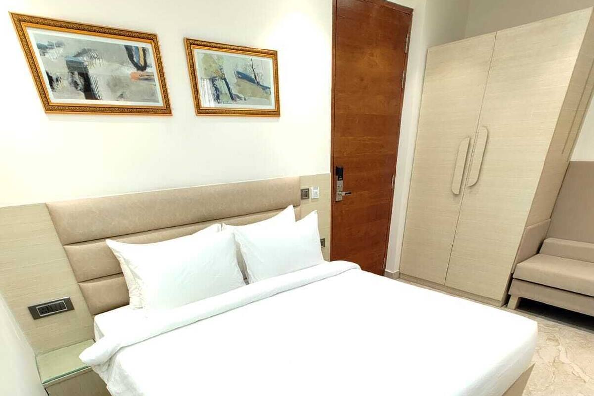 Een ruime slaapkamer met een groot bed, een kledingkast en twee ingelijste kunstwerken aan de muur.