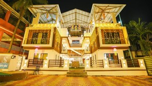 A modern hotel with a symmetrical facade, multiple balconies, and a central entrance. - Singing Sands Beach Resort (Alibag)