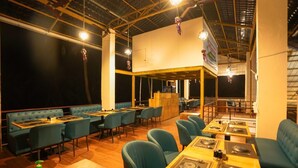 A restaurant with booths and tables, wooden flooring, and hanging decorations. - Singing Sands Beach Resort (Alibag)