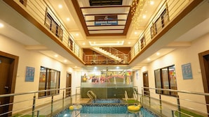 An indoor swimming pool with a glass barrier, a sign for Singing Sands Beach Resort, and a 'Happy Diwali' decoration. - Singing Sands Beach Resort (Alibag)