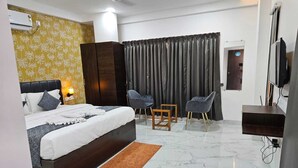 A modern bedroom with a bed, bedside tables, a TV, a wardrobe, and a bathroom. - Singing Sands Beach Resort (Alibag)