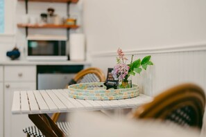 A white table with a decorative tile border, a vase with flowers, and a small sign. - Swank Suites | Step Free King - Pet Friendly (Ashland)
