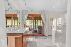 Un baño moderno con un espejo grande, un lavamanos y una zona de ducha.