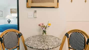 A round table with a floral-patterned tablecloth, two wicker chairs, and a vase with flowers.