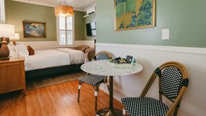 A cozy room with a bed, a round table with chairs, a lamp, and artwork on the wall. - Swank Suites + Private Porch Patio (Ashland)