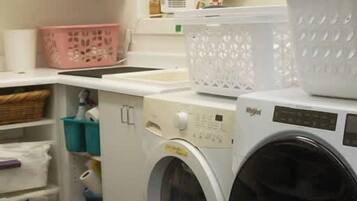 A laundry area with a washing machine and stacked laundry baskets.