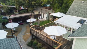Een achtertuin met een houten terras, buitenmeubels en parasols.