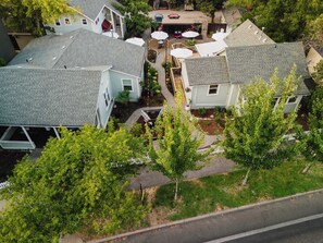 Un quartier résidentiel comprenant plusieurs maisons, une allée pavée et un petit espace extérieur aménagé avec des parasols.