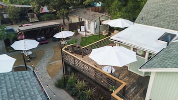 A residential backyard with a wooden deck, outdoor seating, and umbrellas.