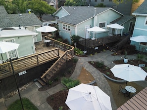 A courtyard with outdoor seating, a wooden deck, and multiple umbrellas. - Swank Boutique Suites | King Suite | DT Ashland (Ashland)