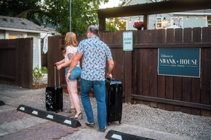 Une clôture en bois avec un panneau indiquant une place de stationnement réservée et un panneau d’accueil pour la résidence Swank.