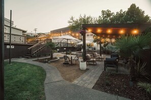 An outdoor patio area with a pergola, seating, and a staircase leading to an upper level.