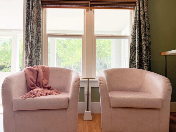 A room with two armchairs facing a large window with a view of trees. - Swank Boutique Suites | King Suite | DT Ashland (Ashland)