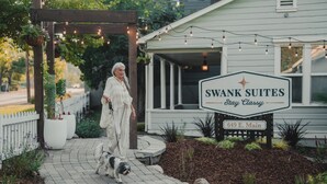 Een bordje voor Swank Suites met een duidelijk adres en een verzorgd buitengebied met een pergola en lichtslingers.