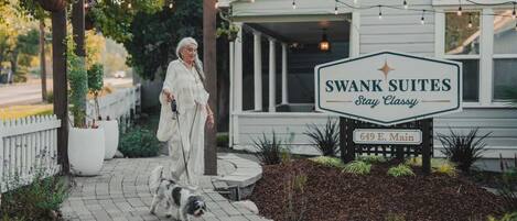 Señal de Swank Suites con un edificio blanco clásico y un camino pavimentado.