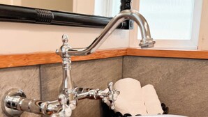 A bathroom with a white marble sink, a black faucet, and a soap dispenser on the counter. - Swank Suites | King with Lux Tub (Ashland)