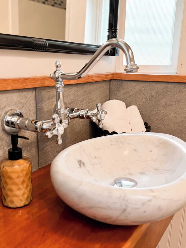 Un baño con un lavabo de mármol blanco, un grifo negro y un dispensador de jabón en la encimera.