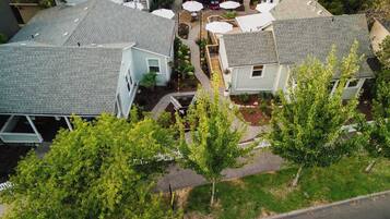 A residential area with multiple houses, a paved driveway, and a small outdoor seating area with umbrellas.