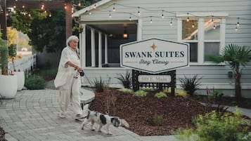 A sign for Swank Suites with a 'Stay Classy' slogan, a paved walkway, and a dog walking.
