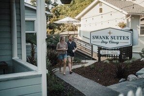 A couple walking towards a property named 'Swank Suites' with a sign indicating 'Stay Classy' and the address '649 E. Main'.