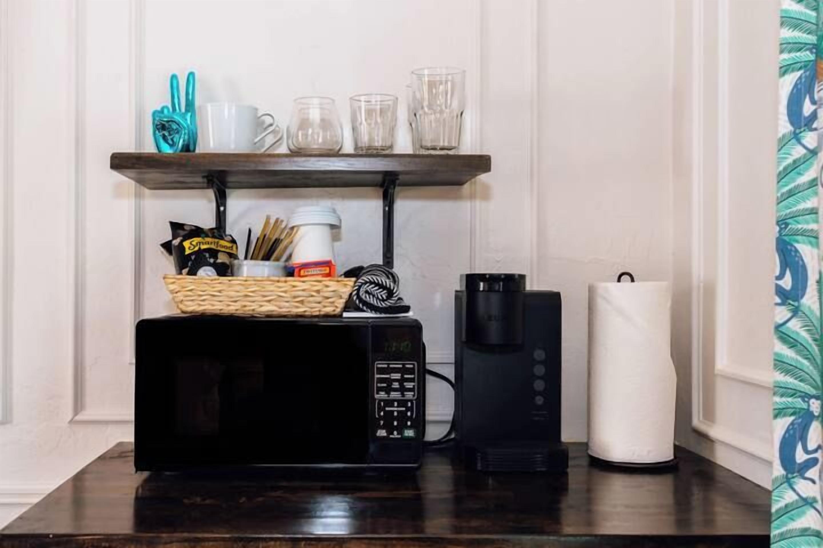 Eine Küchenarbeitsfläche mit einer Mikrowelle, einer Kaffeemaschine und einer Snack-Korb.