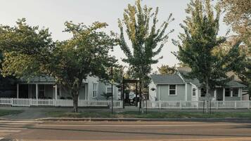Una calle residencial con casas, cerca viva blanca y árboles.