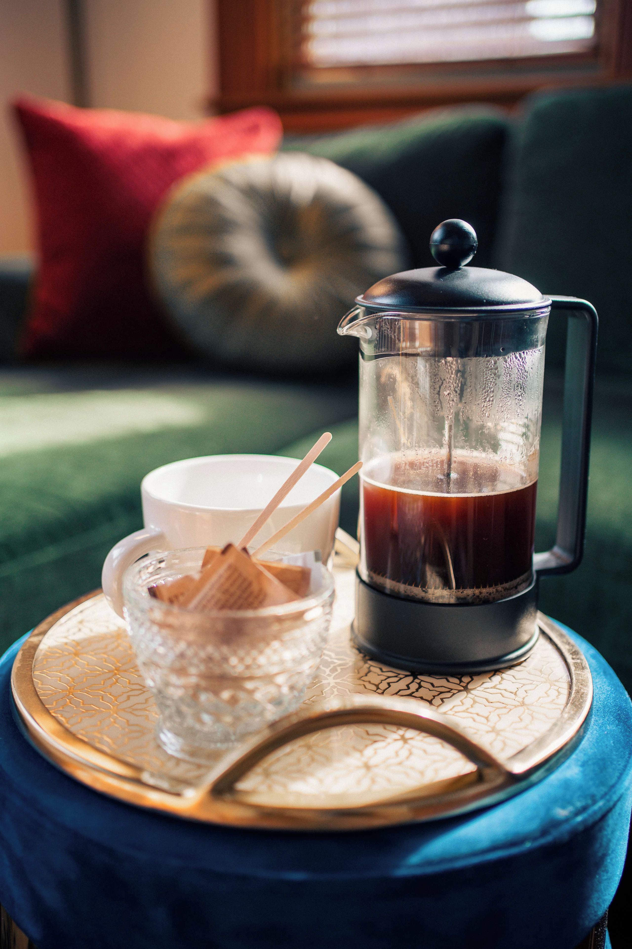 Eine Kaffeemaschine auf einem Tablett mit einer Tasse und einer Zuckerdose.