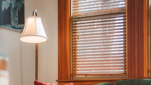 Ein gemütliches Wohnzimmer mit einem grünen Sofa, roten und grünen Kissen, einem blauen Hocker und einer Stehlampe.