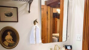 Ein Badezimmer mit einem weißen Waschbecken, einem Spiegel, einem Handtuchhalter und einem gerahmten Bild an der Wand.