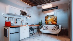 A modern kitchen with a dining area, white cabinetry, a microwave, and a large painting.