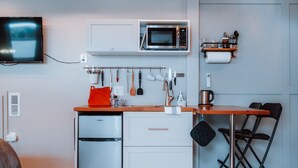 A compact kitchenette with a microwave, small refrigerator, and a wooden countertop.