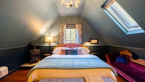 A bedroom with a large bed, a red velvet chair, a wooden chest, and a window with patterned curtains. - Affordable Luxury- One block to Downtown (Ashland)