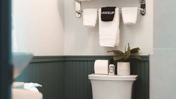 A bathroom with a toilet, a towel rack with towels, and a toilet paper holder.