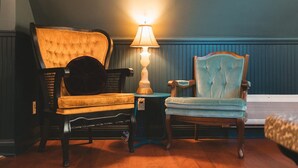 A room with two chairs, one yellow and one blue, a lamp on a small table, and a bed in the background. - Affordable Luxury- One block to Downtown (Ashland)