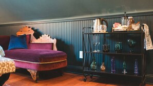 A cozy living room with a purple sofa, a vintage armchair, and a black metal side table with glassware. - Affordable Luxury- One block to Downtown (Ashland)