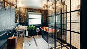 Een moderne badkamer met een vrijstaand bad, een groot raam en een douchecabine van glas.