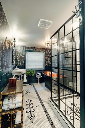A modern bathroom with a glass shower enclosure, a sink with a mirror, and a decorative wall with floral patterns. - Moody Ashland Escape: Luxe Suite, Copper Tub (Ashland)