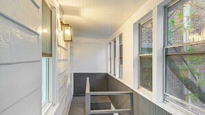 Una escalera estrecha con paredes blancas y barandilla de metal, que conduce a un rellano con varias ventanas.
