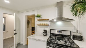 Una cocina moderna con una campana de acero inoxidable, una estufa integrada y una cafetera.
