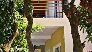 Un edificio con balcón, mobiliario exterior y árboles.