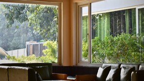 Una habitación con techo de madera, ventanas amplias, ventilador de techo y una mesa con sillas.