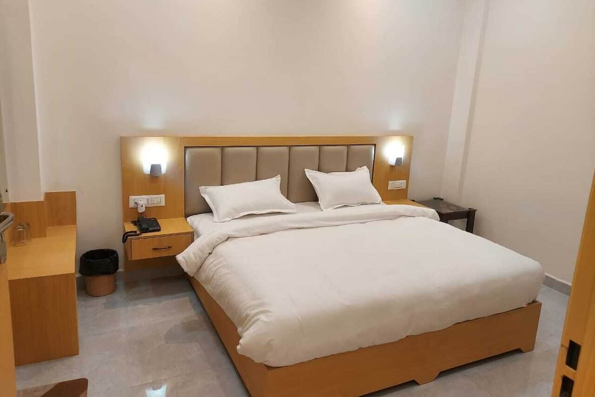 Moderni hotellihuone, jossa on suuri sänky, yöpöydät, puinen yöpöytä ja pieni työpöytä.