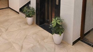 A modern lobby with a marble floor, a black elevator, and two potted plants. - Hotel Innvite (Agra)