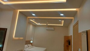 A modern bedroom with a bed, a bedside table, a chair, and a wardrobe. - Hotel Innvite (Agra)