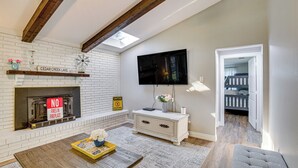 A living room with a fireplace, a television mounted on the wall, and a dining area with a table and chairs. - Waterfront Retreat w/ Hot Tub in Gun Barrel City! (Gun Barrel City)
