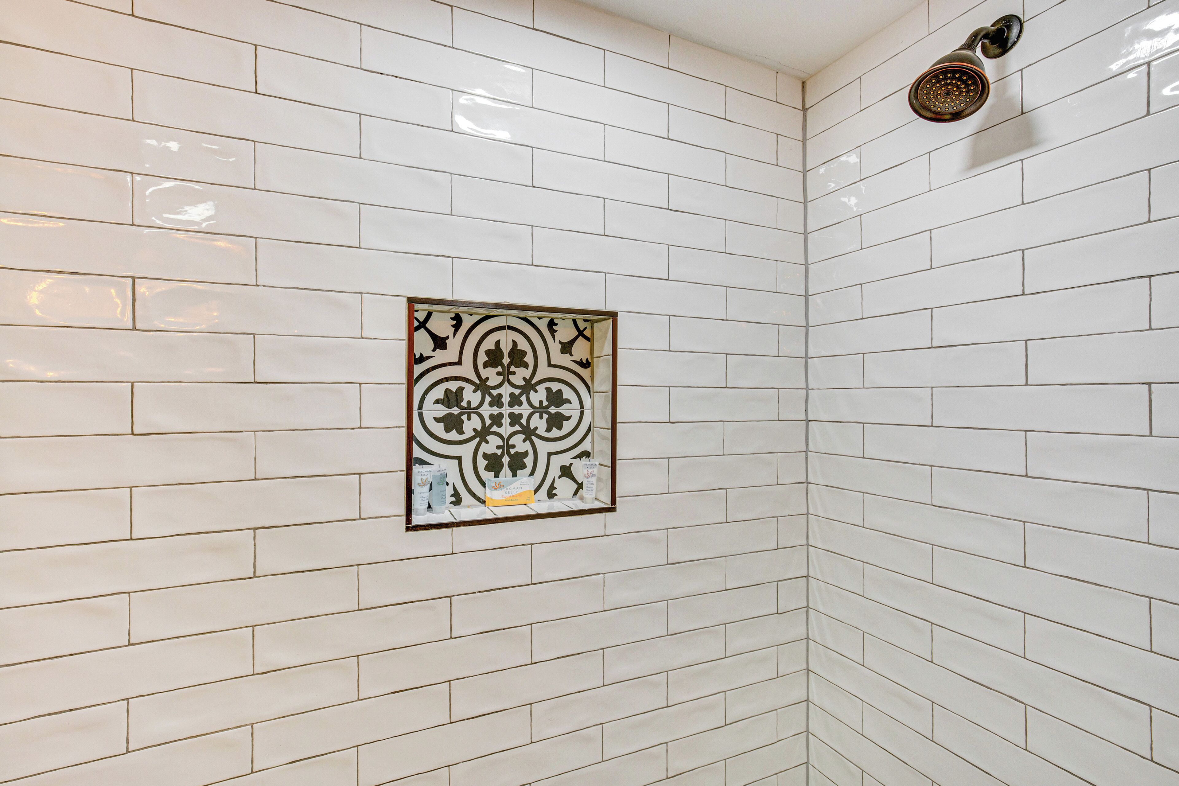 A corner of a bathroom with white subway tiles and a decorative wall piece.