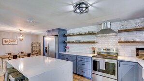 A modern kitchen with a marble island, built-in appliances, and a decorative welcome sign. - Waterfront Retreat w/ Hot Tub in Gun Barrel City! (Gun Barrel City)