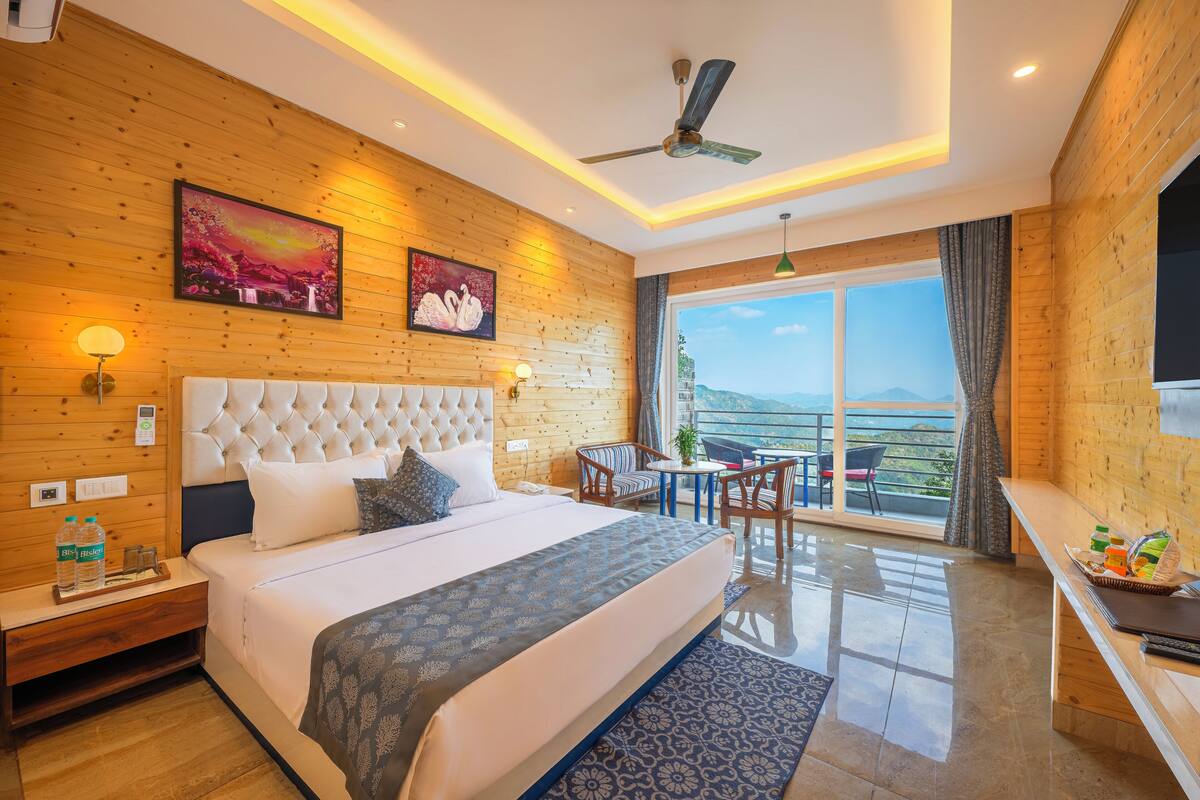 Ein Hotelzimmer mit einem großen Bett, Holzpaneelen, einem Deckenventilator, einem Balkon mit Aussicht und einem Essbereich.