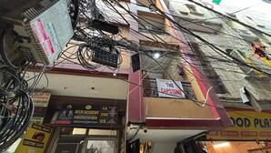 A building with multiple signs, including one for 'The Capstone' and another for 'AFLM Academy'. - The Capstone (New Delhi)